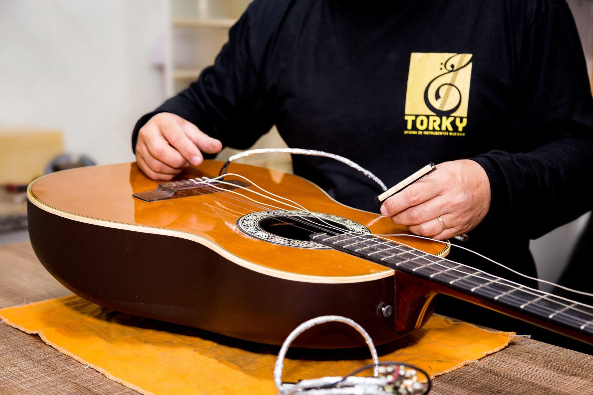 Luthier da Torky fazendo encordoamento de um violão